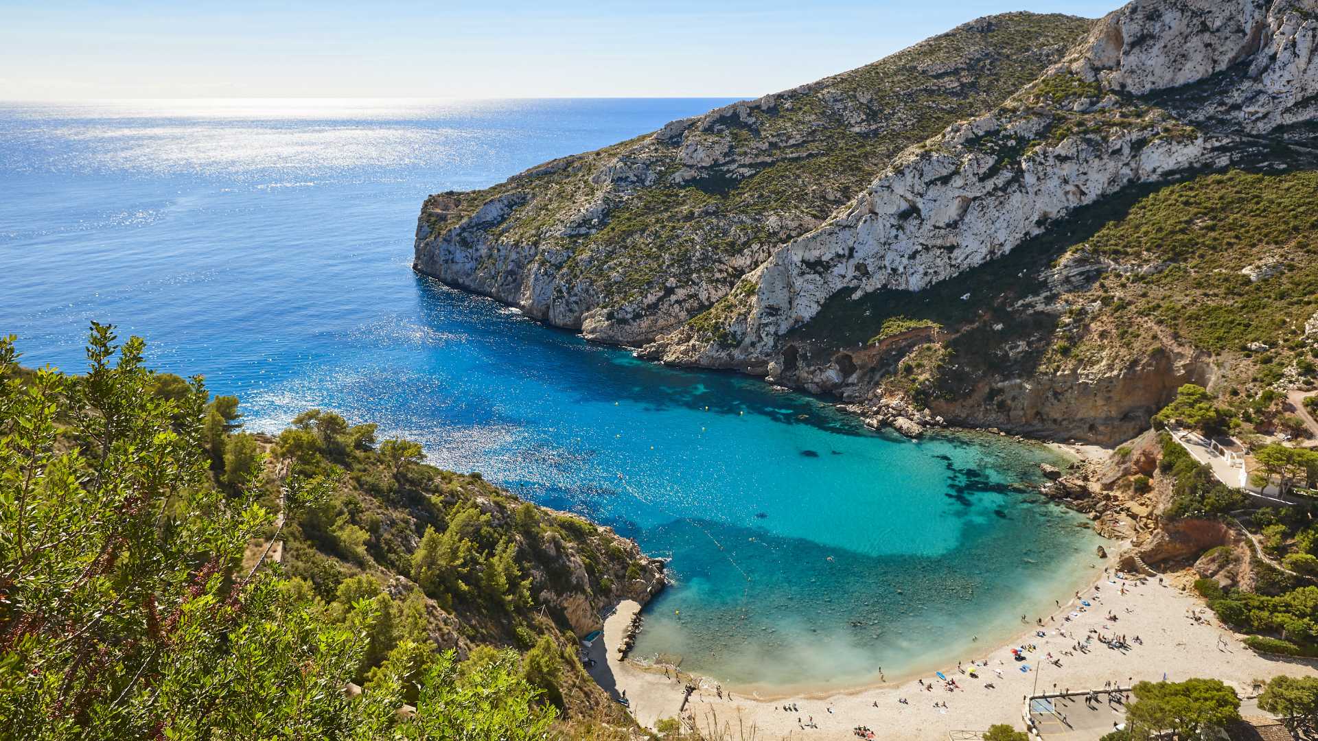 Cala Granadella beach in Jávea with rocky cliffs and clear water