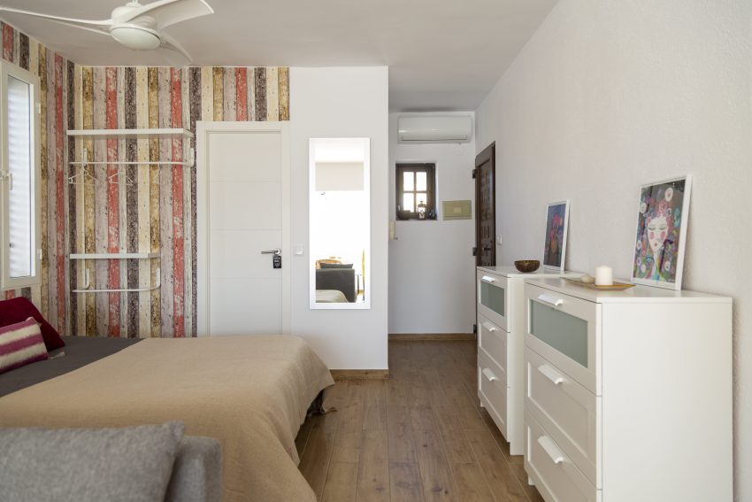 Bedroom with striped wallpaper at apartment Retiro Sol A05 in Dénia